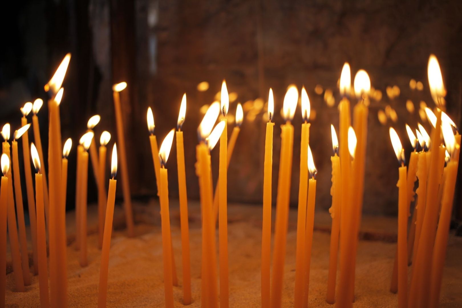Viele brennende orangefarbene Kerzen in einem dunklen Kirchenraum