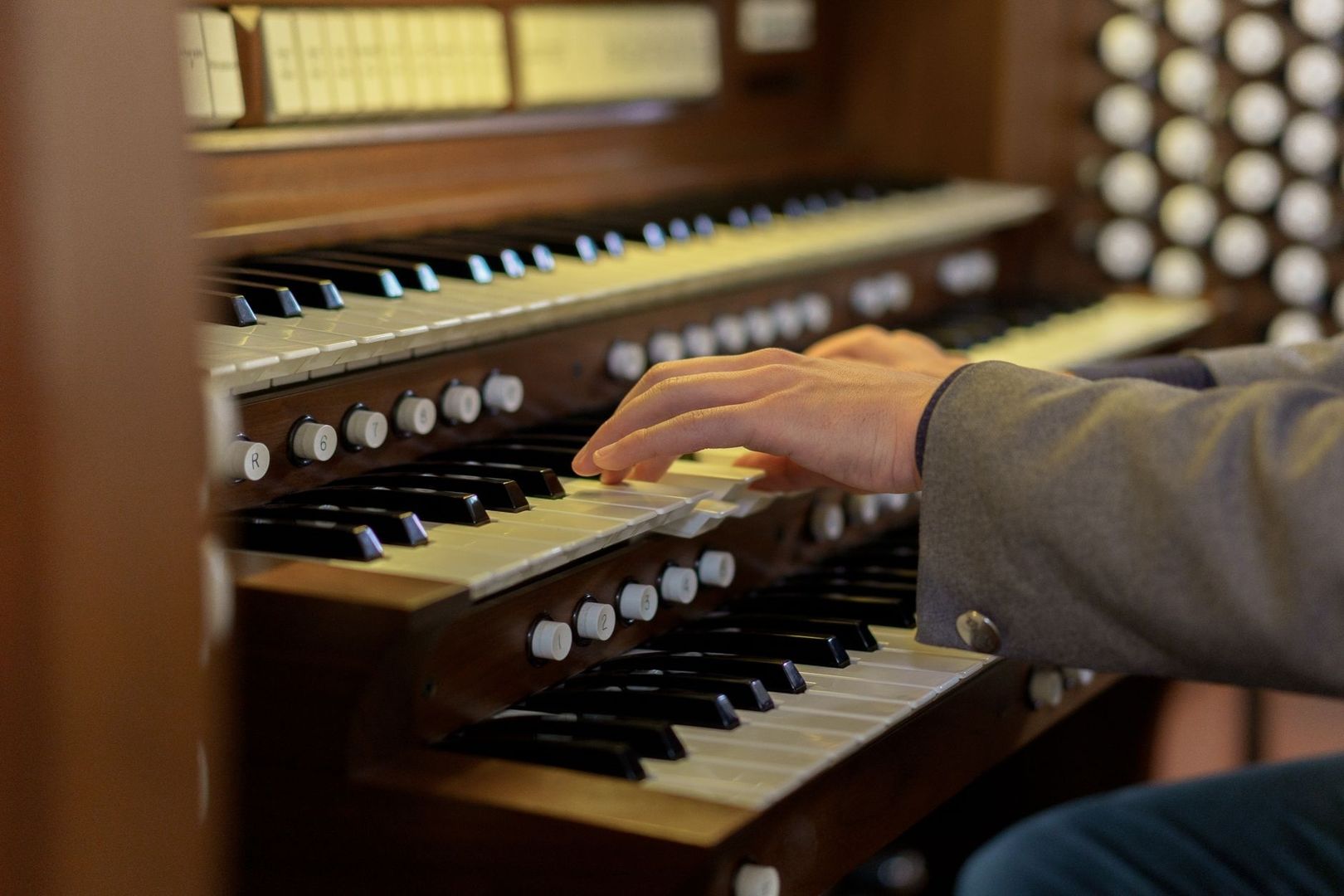 Hände spielen auf den Klaviaturen einer historischen Kirchenorgel